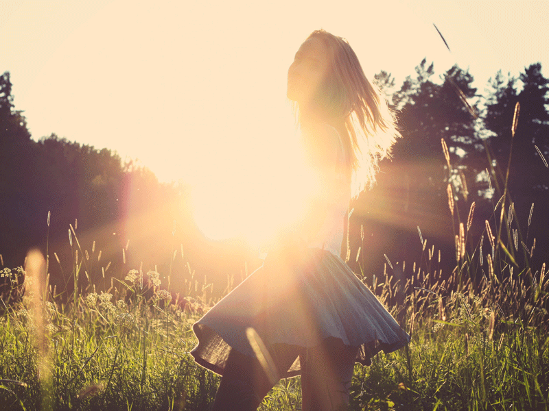 la necesidad de aprender a maternarnos. Una mujer frente a La Luz del sol, paseando por un prado verde 